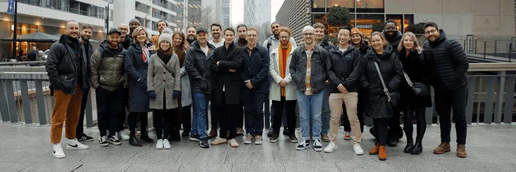 A large group of team members, smiling at the camera with the city behind them.