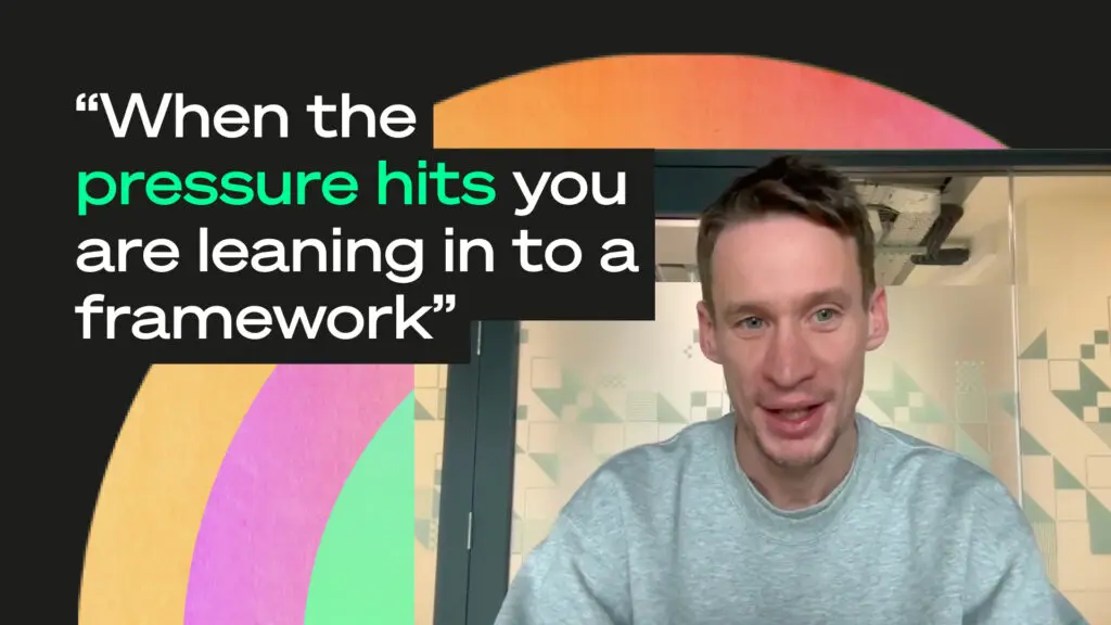 Video-style graphic with a person speaking on the right and bold quote text on the left reading “When the pressure hits you are leaning in to a framework,” with colourful abstract shapes on a dark background.