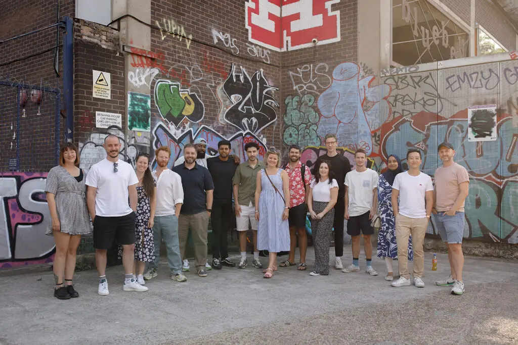 A group of LeftBrain employees stand with graffiti in the background. Celebrating their NCSC Assured Cyber Security Consultancy status.