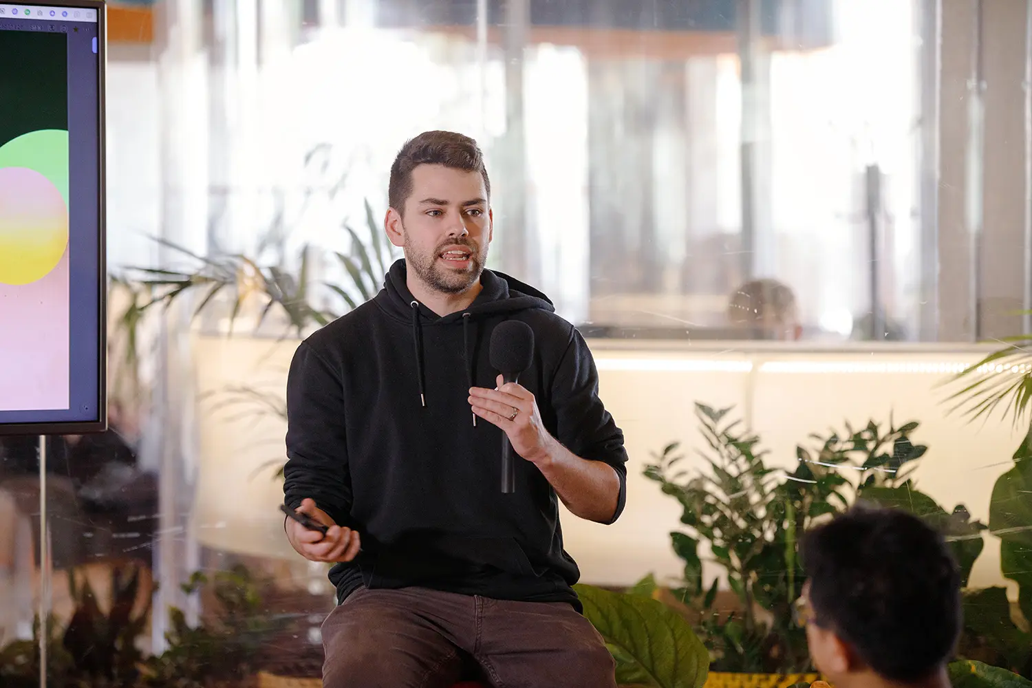 Lucas speaking to a meeting room of people with a mic in hand