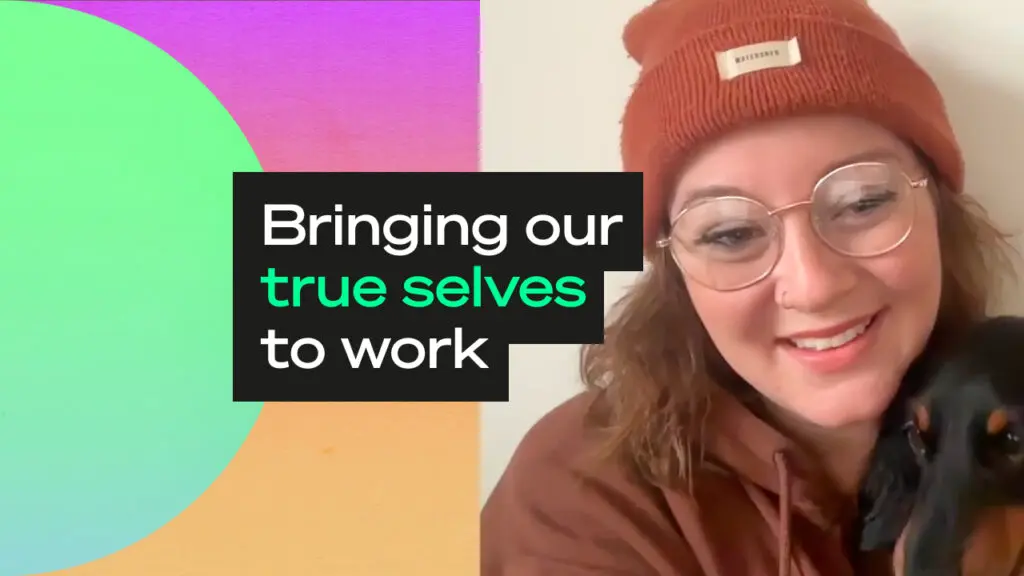 Smiling person wearing glasses and a rust beanie holding a small black dog, beside colourful abstract shapes and the text “Bringing our true selves to work.”