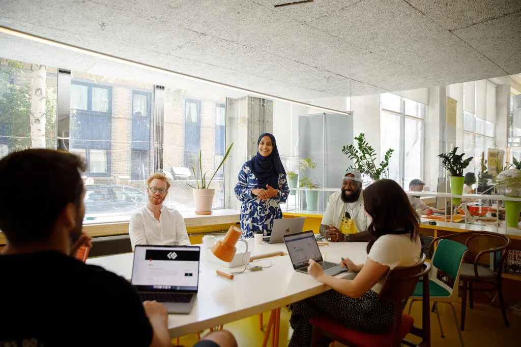 5 people sitting around a conference table in a well lit conference room smiling discussing cyber security strategy.