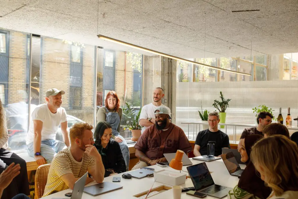 Team of colleagues sat around a conference room table smiling