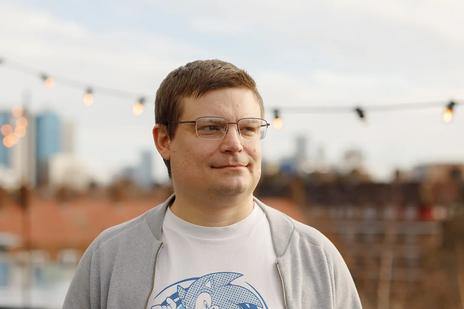 Profile photo of a man outside with cityscape behind