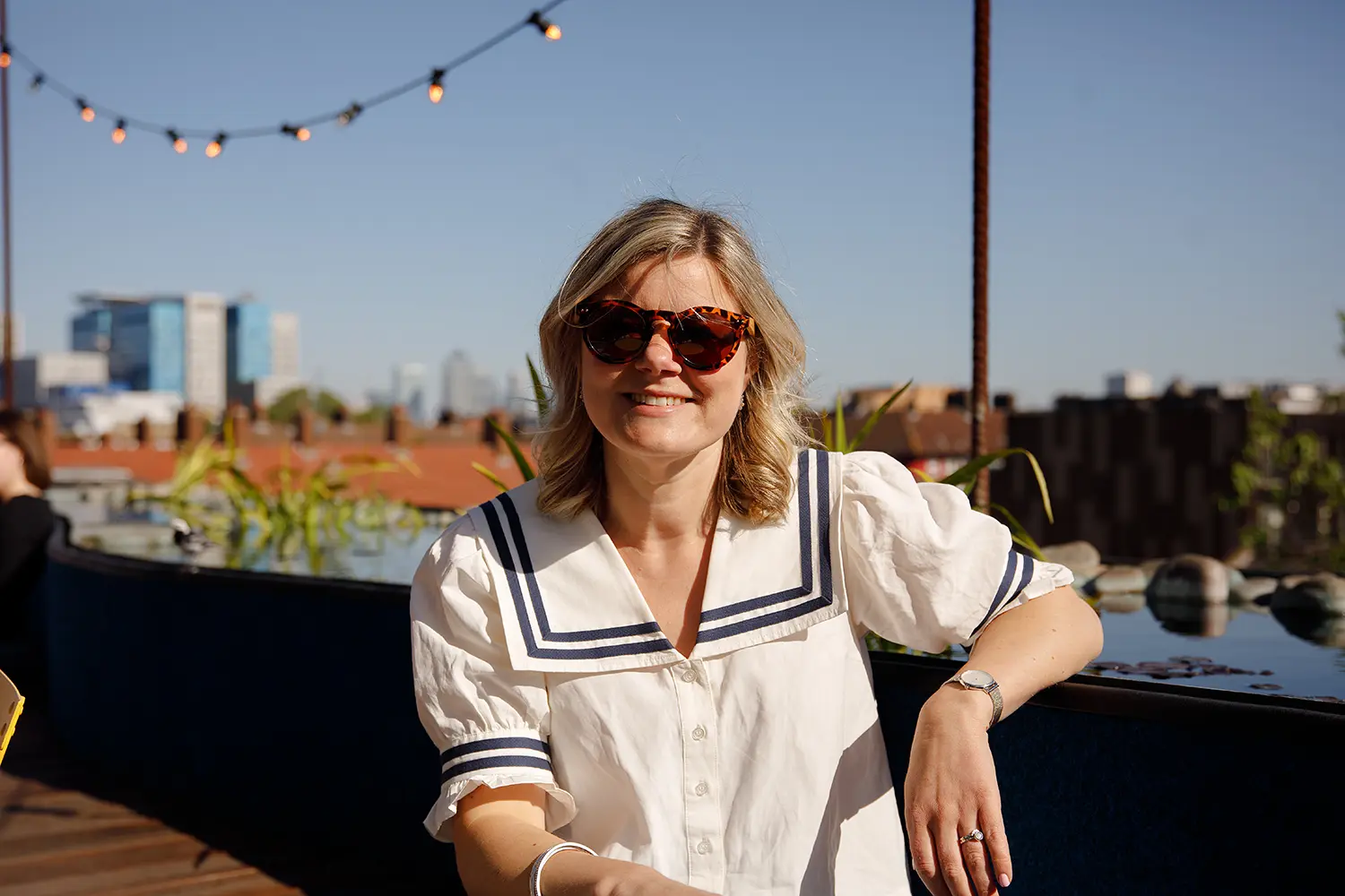 Female smiling while casually sat on a rooftop seating area