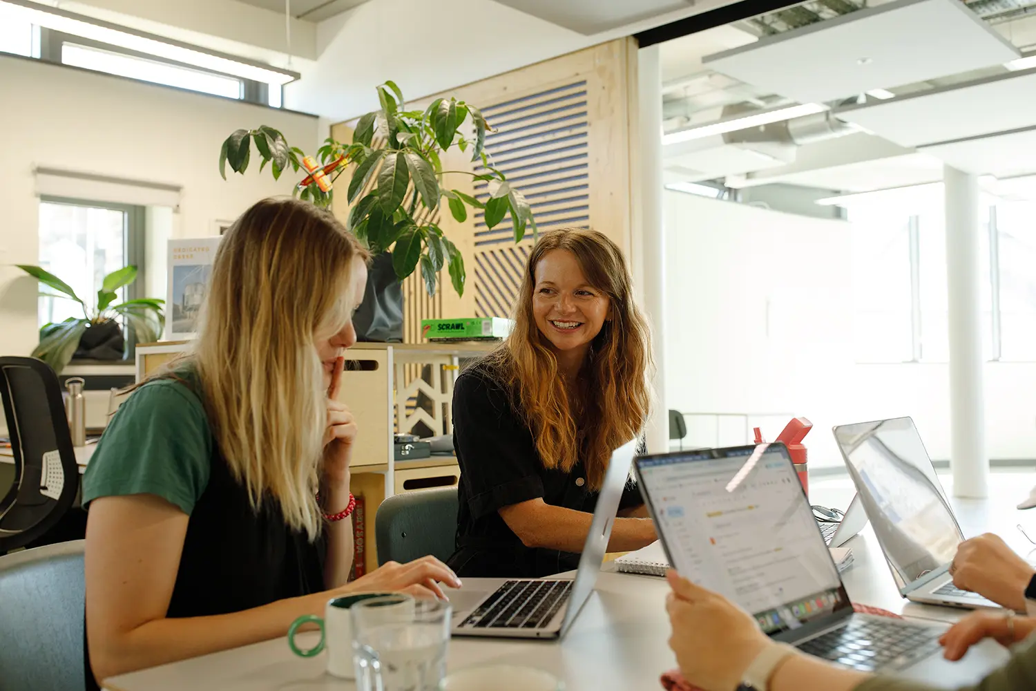 Female smiling while working at a desk next to another woman